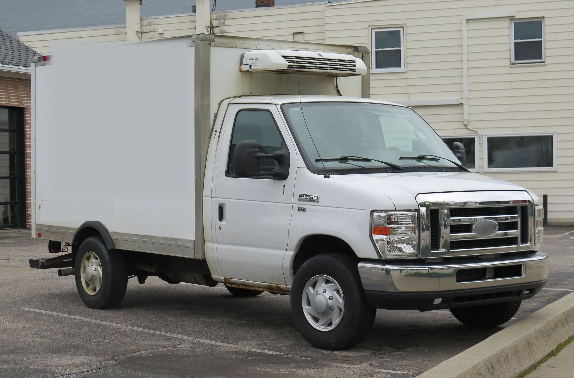 White cutaway box truck with a reefer unit parked on a lot