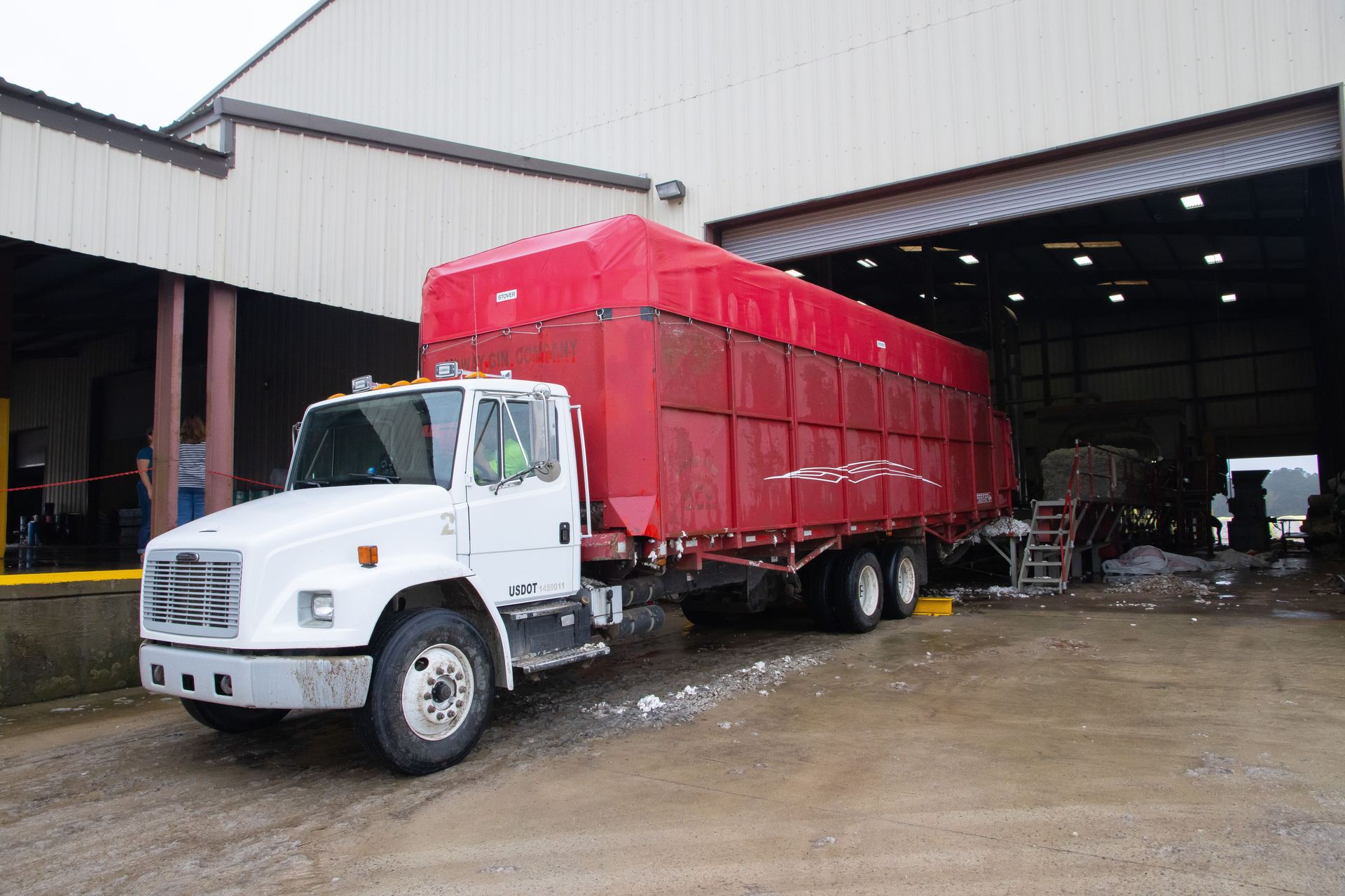 Straight truck with a tarped body outside a warehouse
